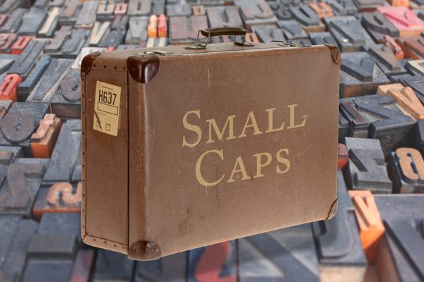 Old leather suitcase with the words Small Caps on it overlaid on old movable wooden type